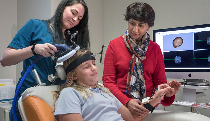 Doctors use of the Transcranial magnetic stimulation tool on a patient, it is a comfortable process for children where they are awake and sit in what looks like a dental chair during the test.